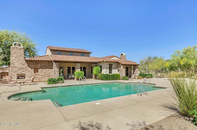 view of pool with a patio and an outdoor stone fireplace