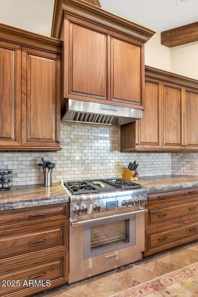 kitchen featuring high end range, tasteful backsplash, exhaust hood, and stone countertops