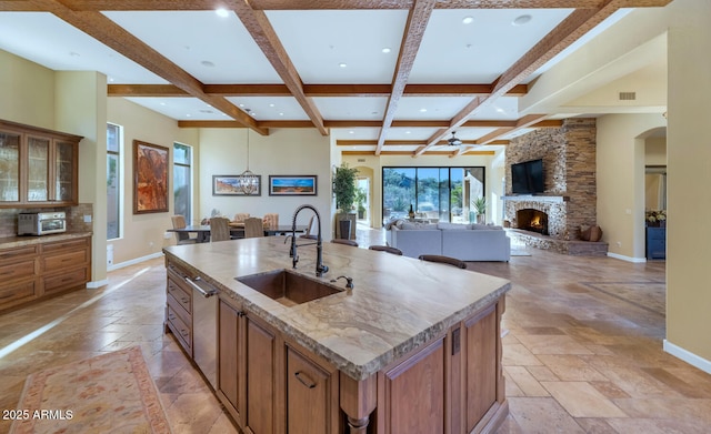 kitchen with coffered ceiling, sink, beam ceiling, and an island with sink