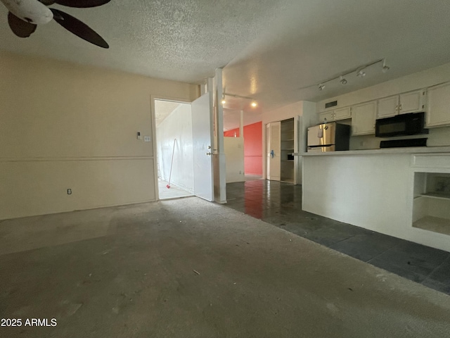 interior space with ceiling fan, unfinished concrete floors, and a textured ceiling