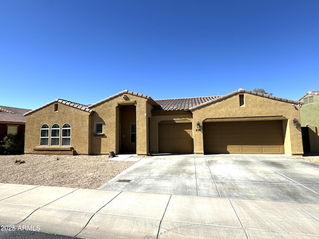 mediterranean / spanish-style house featuring a garage, a tiled roof, concrete driveway, and stucco siding