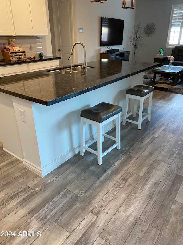 kitchen featuring a kitchen breakfast bar, sink, white cabinets, and light wood-type flooring