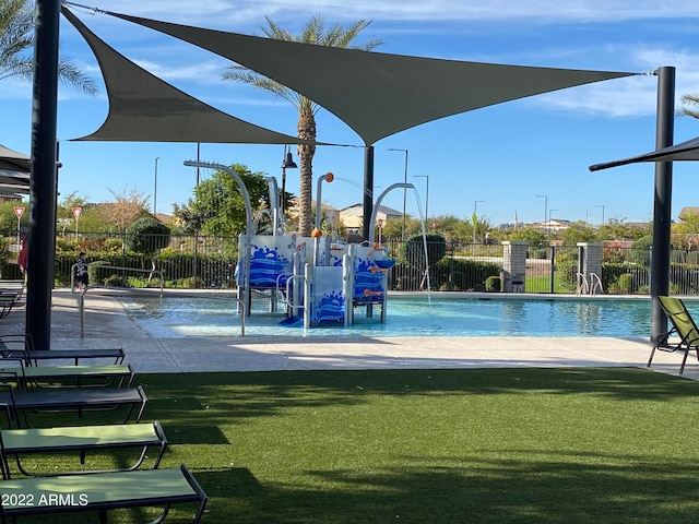 view of playground with a lawn, pool water feature, and a community pool