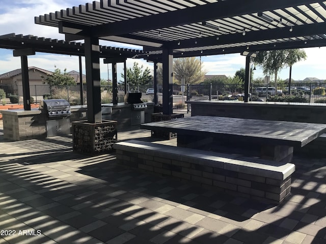 view of patio with a pergola, grilling area, a bar, and an outdoor kitchen