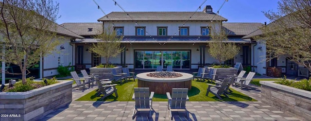 rear view of property featuring a fire pit and a patio