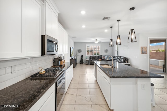 kitchen with appliances with stainless steel finishes, a kitchen island with sink, ceiling fan, sink, and hanging light fixtures