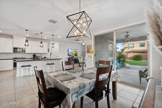 tiled dining room featuring ceiling fan with notable chandelier