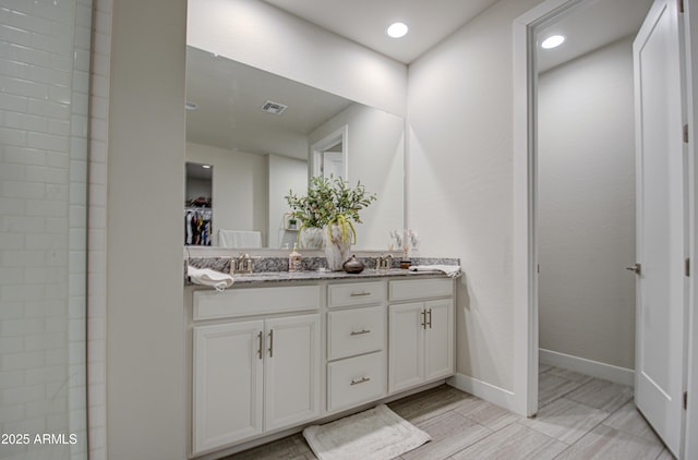 full bathroom with a sink, visible vents, baseboards, a spacious closet, and double vanity