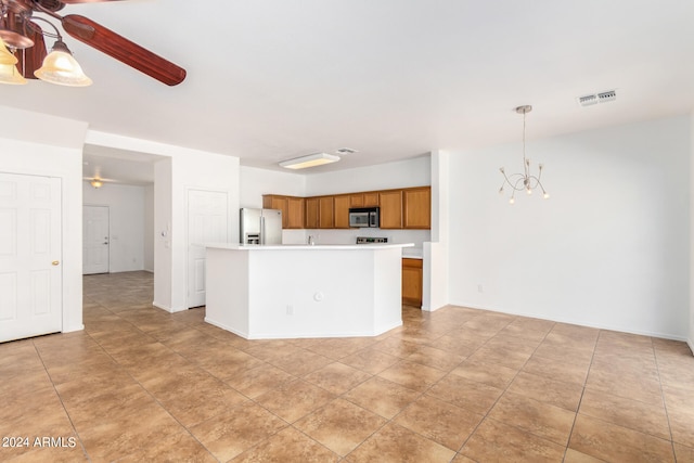 kitchen featuring ceiling fan with notable chandelier, appliances with stainless steel finishes, decorative light fixtures, and a kitchen island