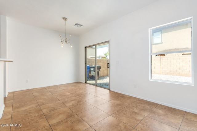 unfurnished room featuring an inviting chandelier and light tile patterned flooring