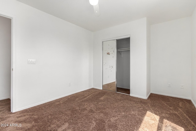 unfurnished bedroom featuring ceiling fan, dark colored carpet, and a closet