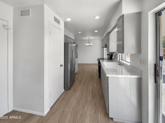 kitchen with electric range, visible vents, gray cabinetry, a sink, and freestanding refrigerator