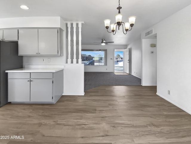 kitchen featuring visible vents, ceiling fan with notable chandelier, wood finished floors, freestanding refrigerator, and light countertops