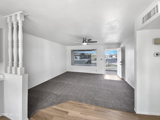 unfurnished living room with visible vents, carpet floors, a ceiling fan, and wood finished floors