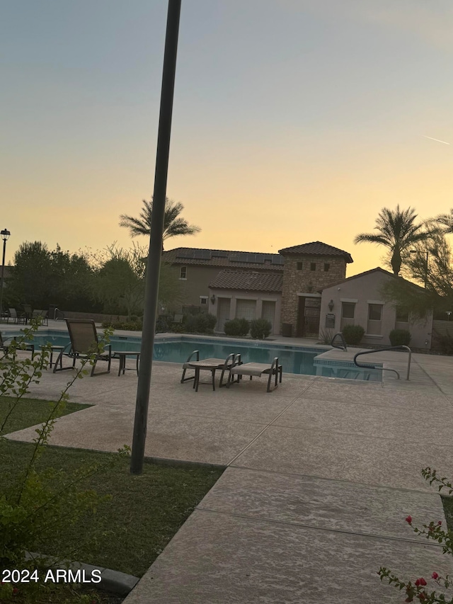 pool at dusk featuring a patio