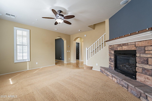 unfurnished living room with ceiling fan and a stone fireplace