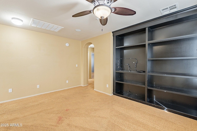 carpeted spare room featuring built in shelves and ceiling fan