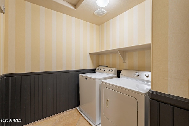 clothes washing area with light tile patterned floors, washer and dryer, and a textured ceiling