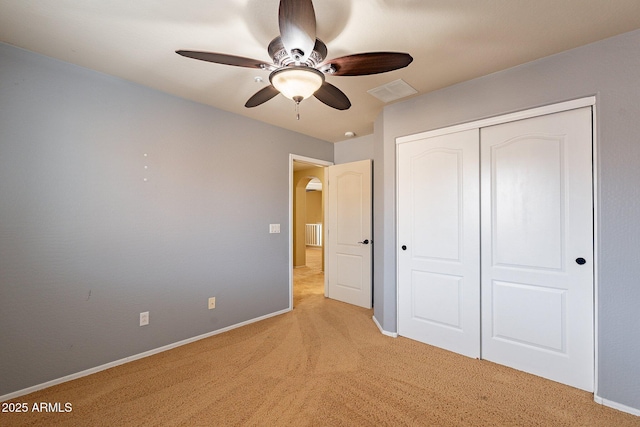 unfurnished bedroom with ceiling fan, a closet, and light colored carpet