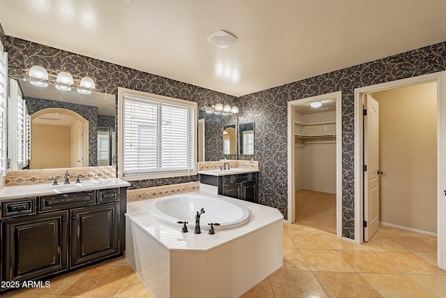 bathroom with tile patterned floors, a bathing tub, and vanity