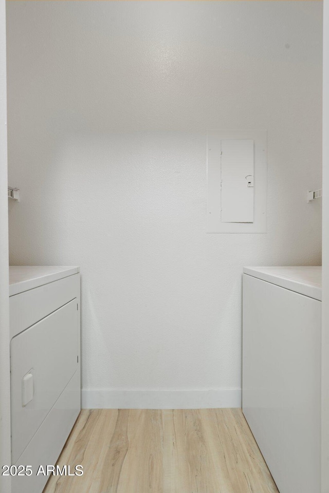 laundry room featuring washer and dryer, electric panel, and light wood-type flooring