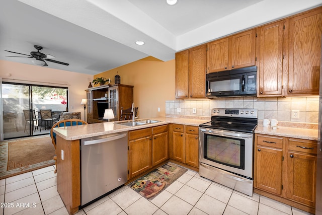 kitchen with kitchen peninsula, ceiling fan, appliances with stainless steel finishes, decorative backsplash, and sink