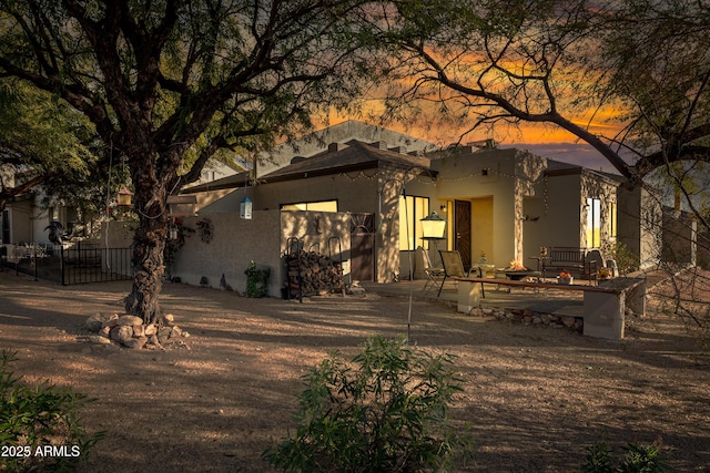 back house at dusk featuring a fire pit and a patio