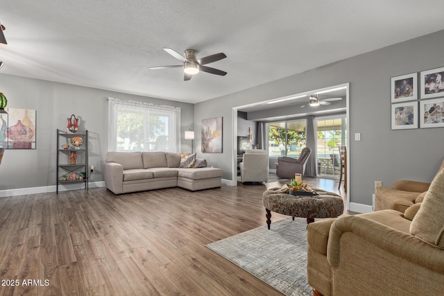 living room featuring ceiling fan, wood-type flooring, and a textured ceiling