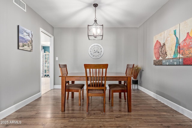 dining area with dark hardwood / wood-style floors and an inviting chandelier