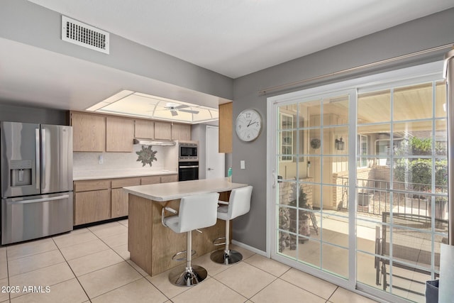 kitchen with tasteful backsplash, kitchen peninsula, light tile patterned floors, and appliances with stainless steel finishes