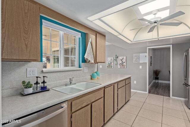 kitchen featuring appliances with stainless steel finishes, backsplash, a skylight, sink, and light tile patterned floors