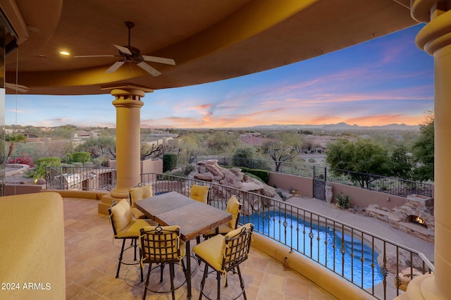 balcony at dusk with ceiling fan and a fenced in pool