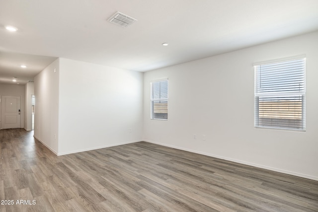 empty room featuring baseboards, recessed lighting, wood finished floors, and visible vents