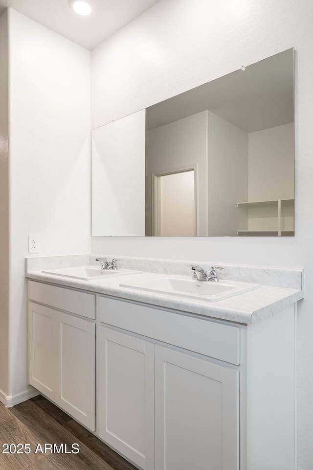 full bathroom featuring double vanity, a sink, baseboards, and wood finished floors
