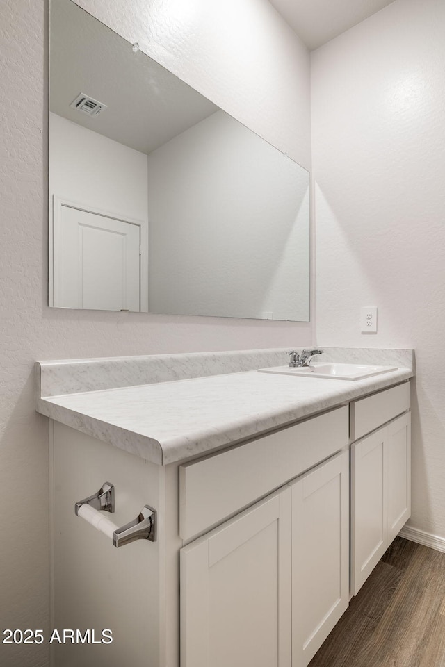 bathroom with baseboards, visible vents, wood finished floors, and vanity