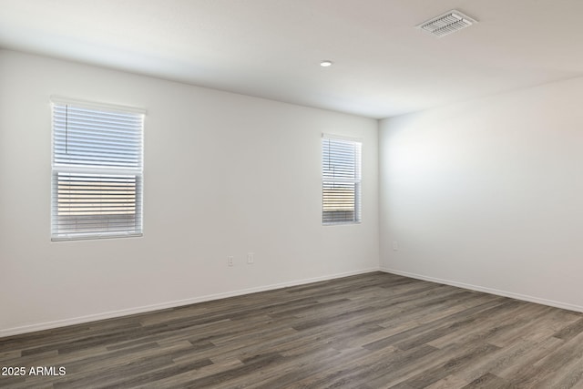 unfurnished room with dark wood-style flooring, baseboards, visible vents, and recessed lighting