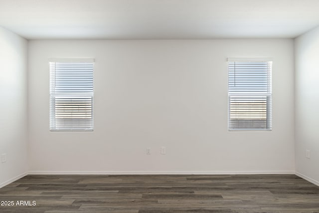 unfurnished room with dark wood-style flooring, baseboards, and a wealth of natural light