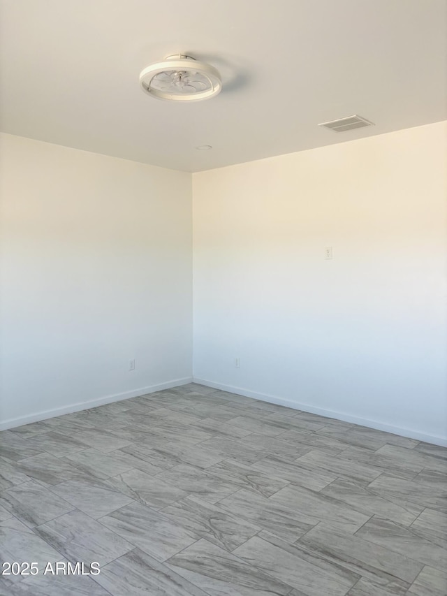 unfurnished room with baseboards and visible vents