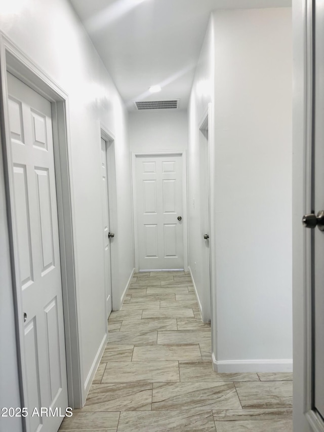 hallway featuring visible vents and baseboards