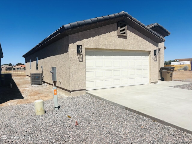 view of home's exterior with a tiled roof, cooling unit, concrete driveway, an attached garage, and stucco siding