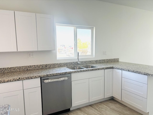 kitchen with dishwasher, white cabinetry, light stone countertops, and a sink