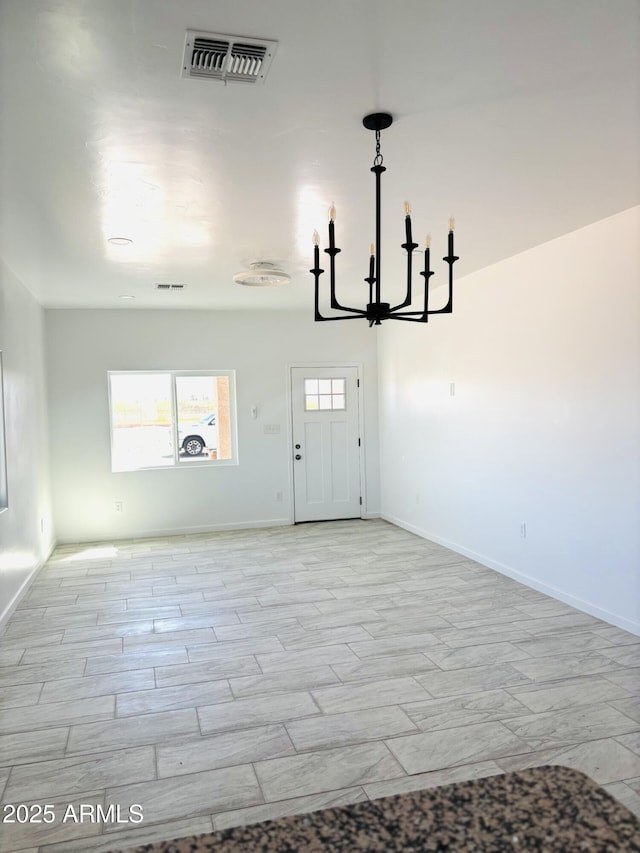 unfurnished dining area with baseboards, a notable chandelier, and visible vents