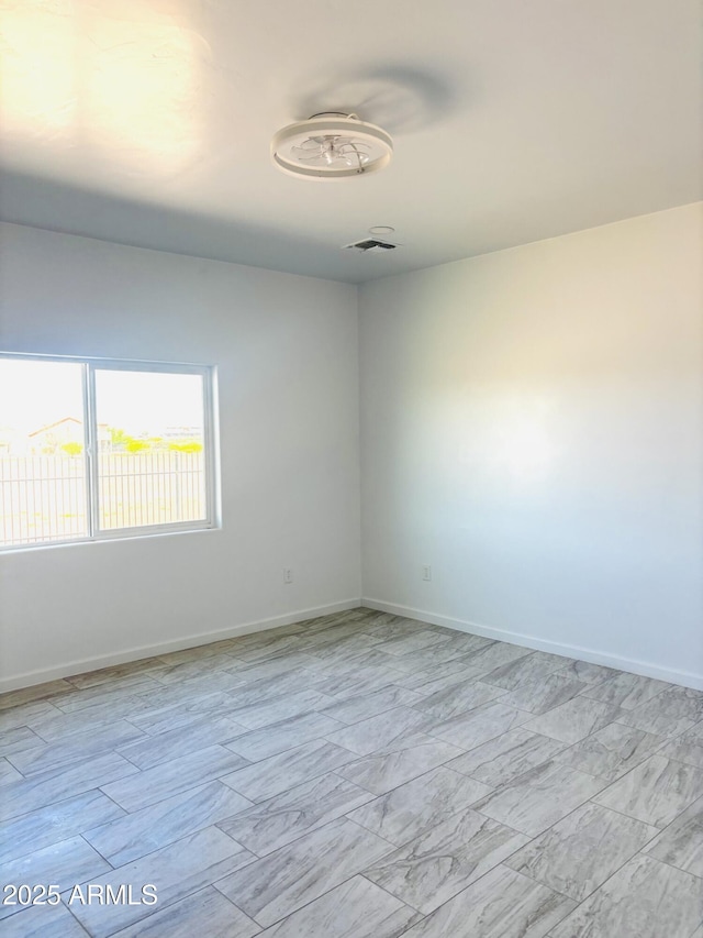 spare room featuring baseboards and marble finish floor