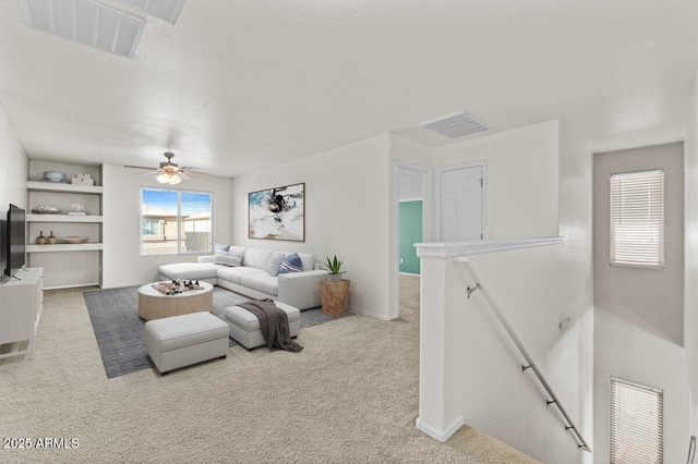 living room featuring a textured ceiling, carpet floors, and ceiling fan