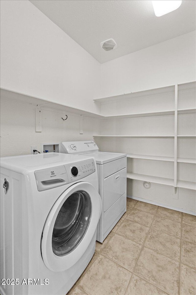 clothes washing area featuring washing machine and clothes dryer and light tile patterned floors