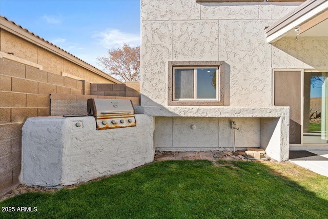 view of side of home with a lawn and an outdoor kitchen