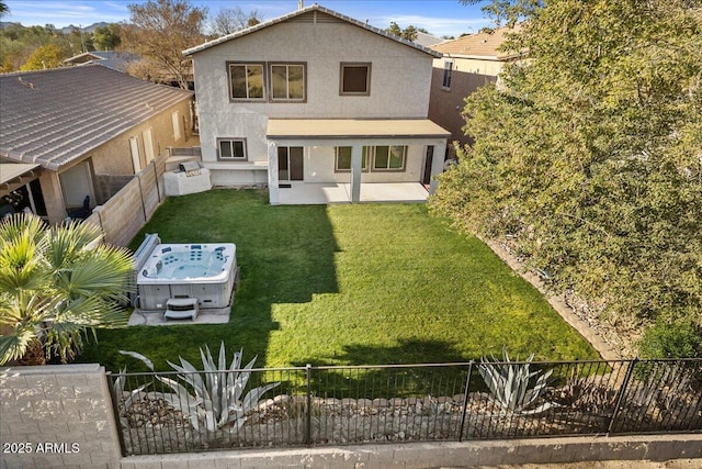 rear view of house with a hot tub, a lawn, and a patio area