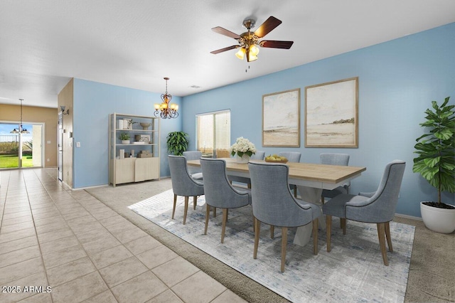 tiled dining space with plenty of natural light and ceiling fan with notable chandelier