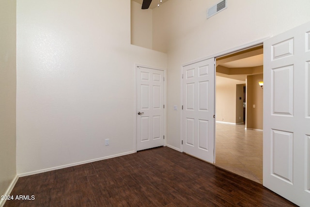 spare room featuring dark wood-type flooring and a high ceiling