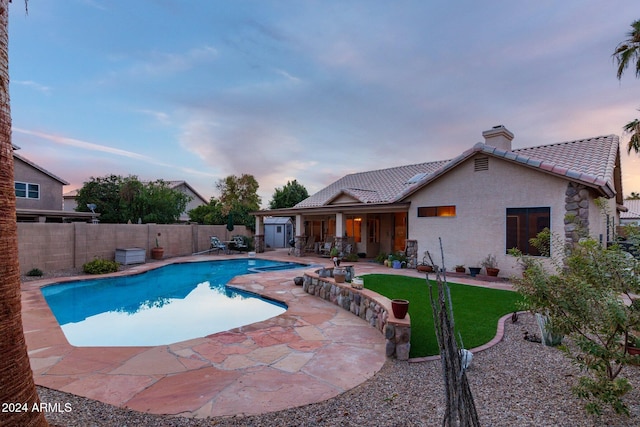 pool at dusk featuring a patio area and a yard